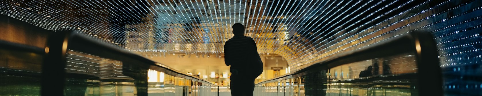 A silhouette walking through the illuminated light tunnel at the National Gallery of Art.