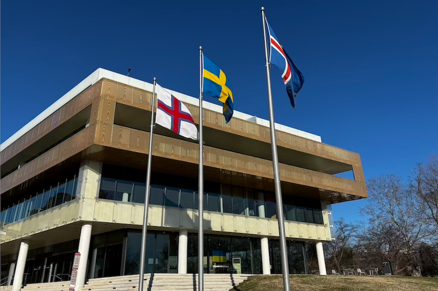 A modern building with three flags out front.