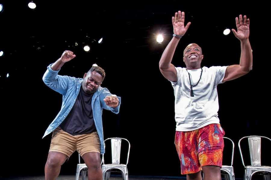 Two performers animatedly act out a comedic scene on stage under bright lights at Washington Improv Theater.