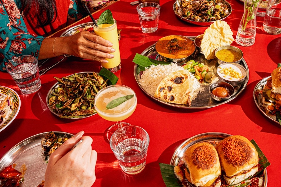 Vibrant Indian meal spread at Chai Pani in Union Market featuring thalis, snacks and colorful drinks on a bright red table.