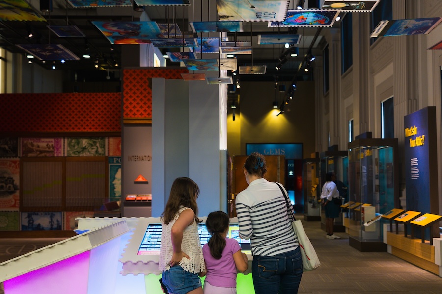 A family explores an interactive stamp-themed display at the Smithsonian National Postal Museum.
