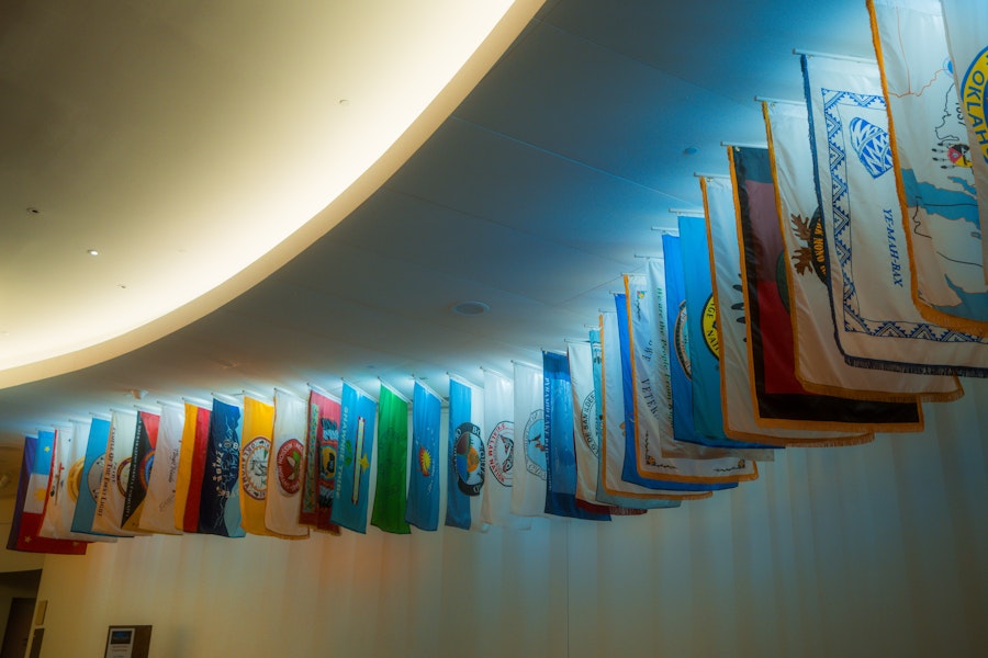 Colorful tribal nation flags hanging from the ceiling inside the National Museum of the American Indian.