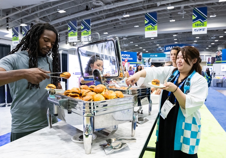 People serve themselves sliders from a buffet station at a the Walter E. Washington conference expo hall.