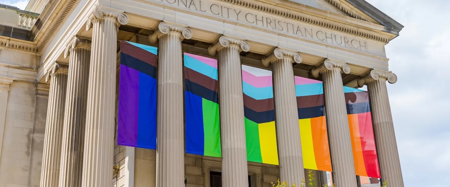 The columns of a historic church decorated with LGBTQIA+ flags.