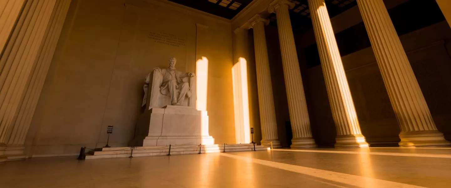 The statue of Abraham Lincoln bathed in golden light inside the Lincoln Memorial.