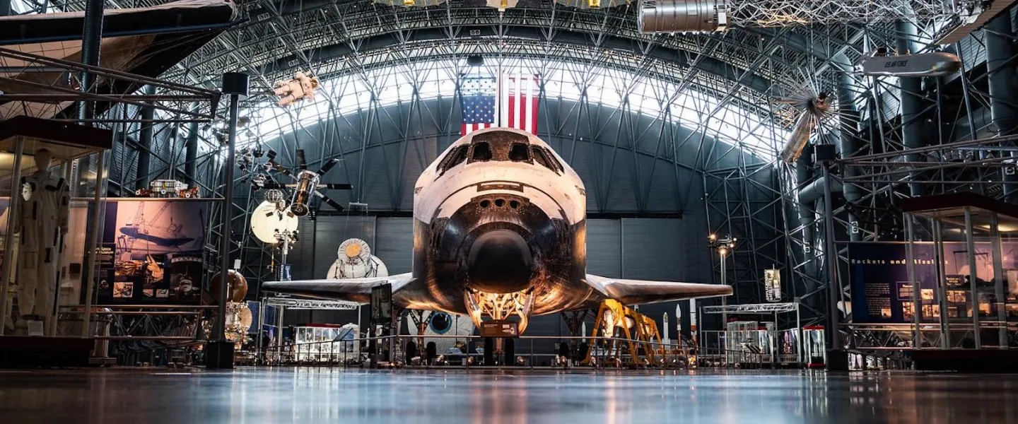 The Space Shuttle Discovery displayed inside the Smithsonian’s Steven F. Udvar-Hazy Center with spacecraft exhibits surrounding it.