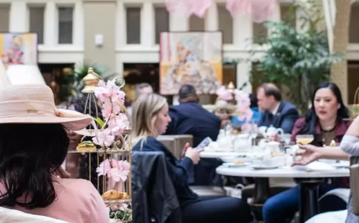 An elegant hotel lobby filled with folks enjoying afternoon tea. 
