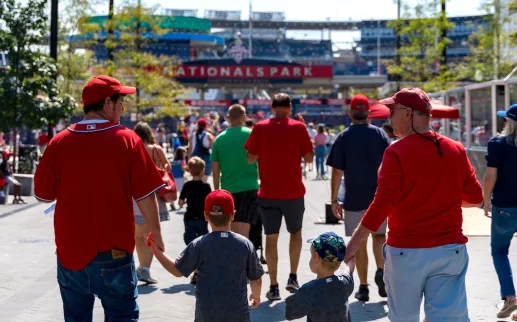 Families in red jerseys walking toward Nationals Park for a baseball game.